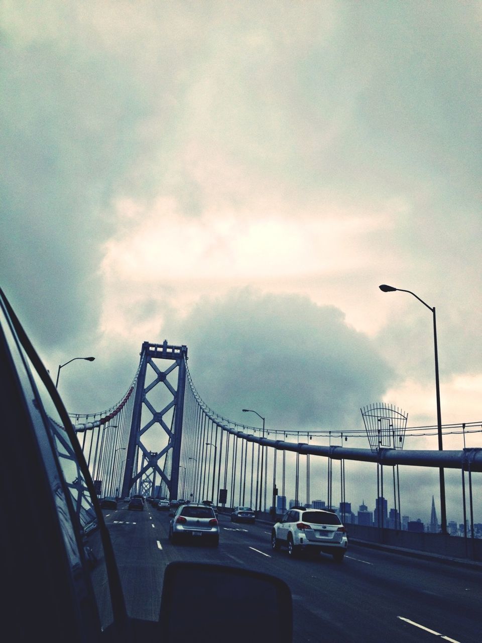 transportation, car, land vehicle, sky, street light, road, mode of transport, cloud - sky, street, built structure, architecture, cloudy, road marking, connection, low angle view, the way forward, on the move, cloud, city, traffic