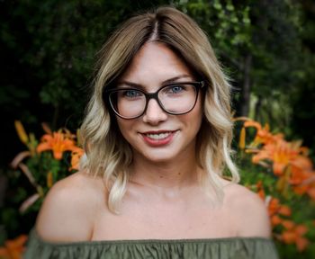 Close-up portrait of young woman wearing eyeglasses against plants