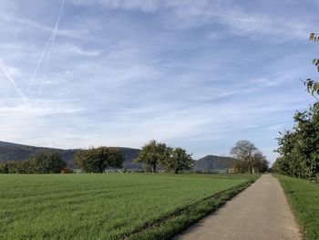 Road amidst field against sky