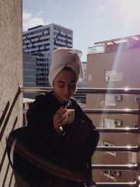 Young woman drinking coffee while sitting at balcony