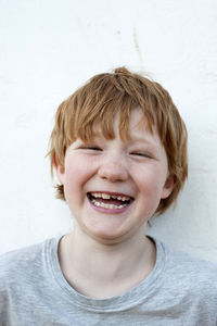 Cheerful redhead boy in front of wall outdoors