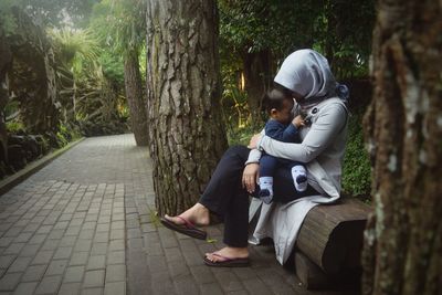 Full length of mother and son sitting at park