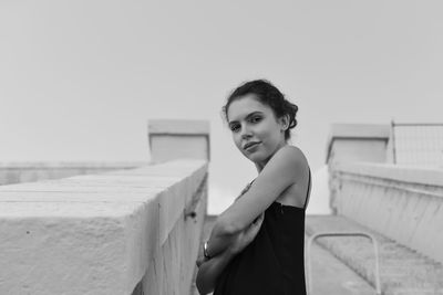 Portrait of smiling young woman standing against sky