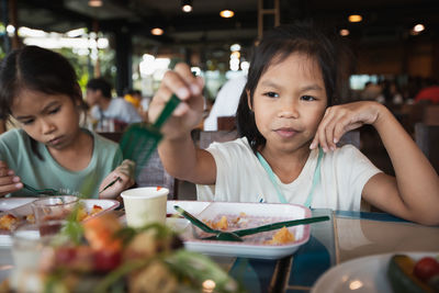 Portrait of cute girl eating food in restaurant