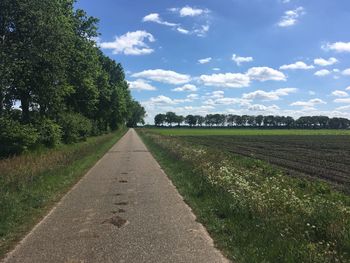 Road amidst field against sky