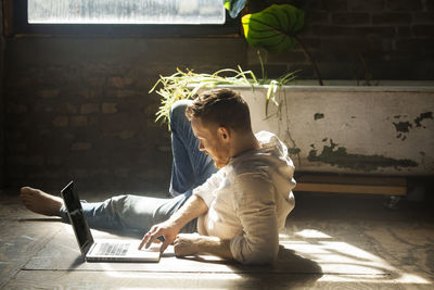 Man using laptop computer while reclining on floor at home