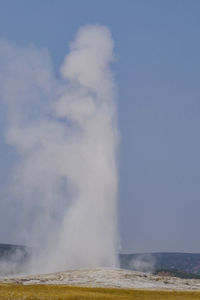 Steam emitting from volcanic landscape against clear sky