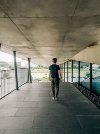 A man walks down the outer corridor of the building.
