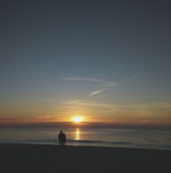 Silhouette of man on beach against sky during sunset