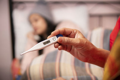 Cropped hand of woman holding thermometer