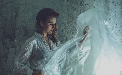 Woman with plastic against wall