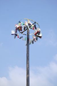 Low angle view of various objects hanging on pole against blue sky