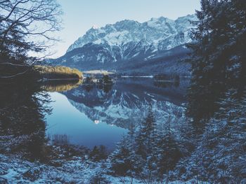 Scenic view of lake by snowcapped mountains against sky