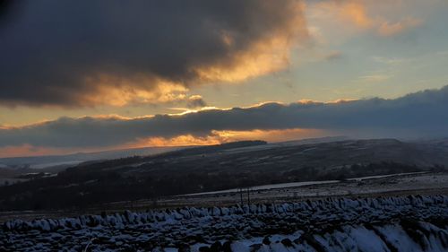 Scenic view of snow covered land against sky during sunset