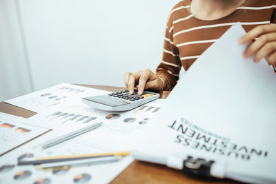 Midsection of woman holding paper with text on table