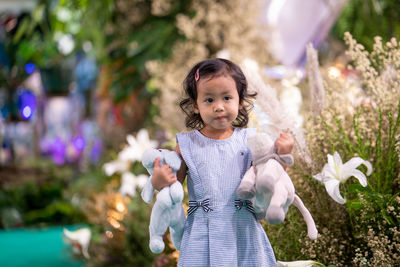 Cute girl holding stuffed toys while standing outdoors