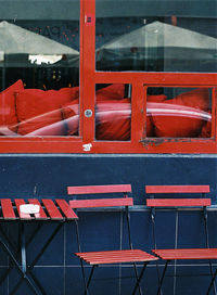 Close-up of empty chairs and table at sidewalk cafe in city