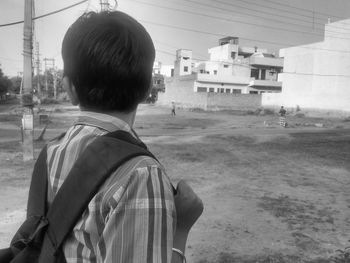 Rear view of a man standing by built structure