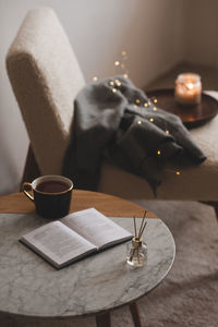 Bamboo sticks in bottle with scented candles and cup of tea on marble table closeup. home aroma. 