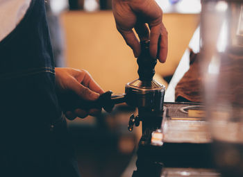 Midsection of barista making coffee in cafe