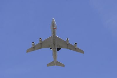 Low angle view of airplane flying against clear blue sky