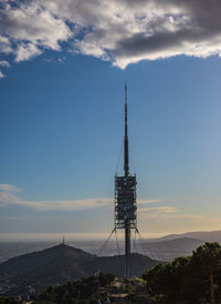 Communications tower on building against cloudy sky