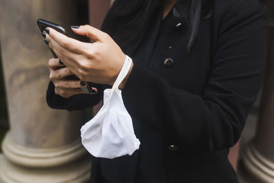 Hands typing on the phone with a mask