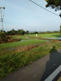 Road amidst field against sky