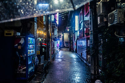 Illuminated street amidst buildings in city at night