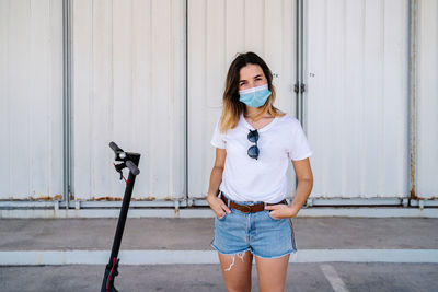 Portrait of young woman standing against wall