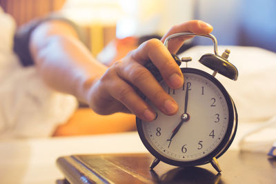 Close-up of person holding clock on table