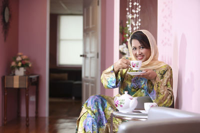 Portrait of woman drinking coffee while sitting at home