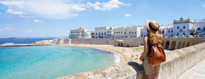 Rear view of woman standing by sea against sky