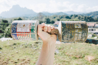 Close-up of hand holding paper against mountain