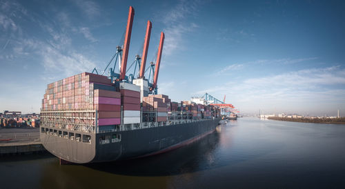 Cranes at commercial dock against sky