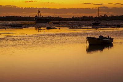 Boat moored on sea against sky during sunset