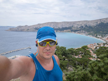 Portrait of smiling man wearing sunglasses against sea and sky