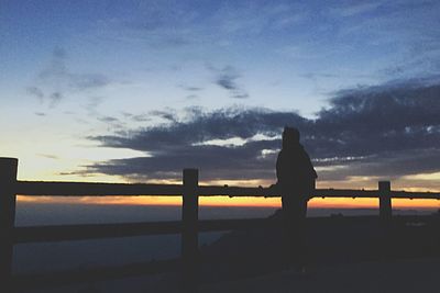 Silhouette woman standing by sea against sky during sunset