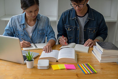 Man and woman using mobile phone while sitting on table