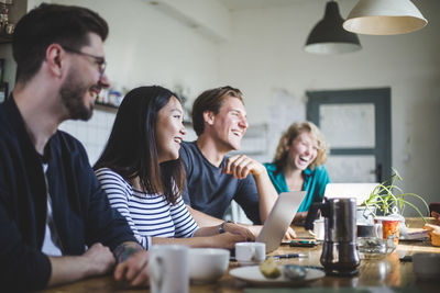 Team of professional computer hackers laughing while sitting at desk in office