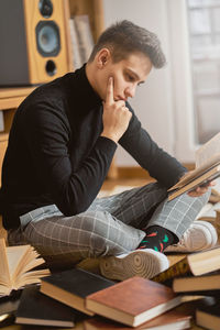 Man reading book while sitting on floor at home