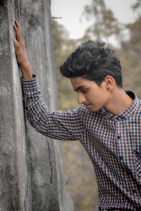 Teenage boy standing by wall