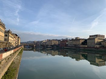 Buildings by river against sky in city