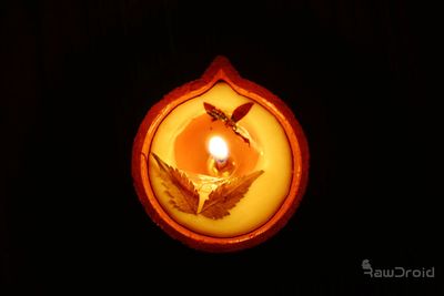 Close-up of lit candle against black background