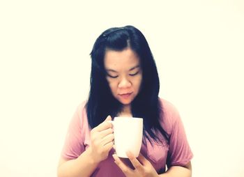Young woman drinking coffee cup against white background