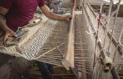 Midsection of man weaving textile