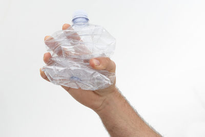 Close-up of hand holding plastic against white background