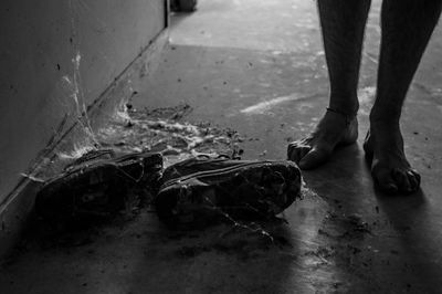 Low section of man standing by abandoned shoes with spider web