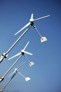 Low angle view of windmill against clear blue sky