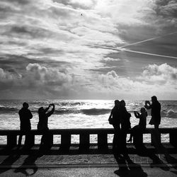 Silhouette men standing on beach against sky